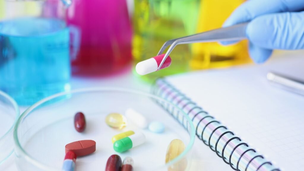 A laboratory scene where a pill is being picked up with tweezers in front of colorful glass beakers filled with chemical solutions, surrounded by various pills.