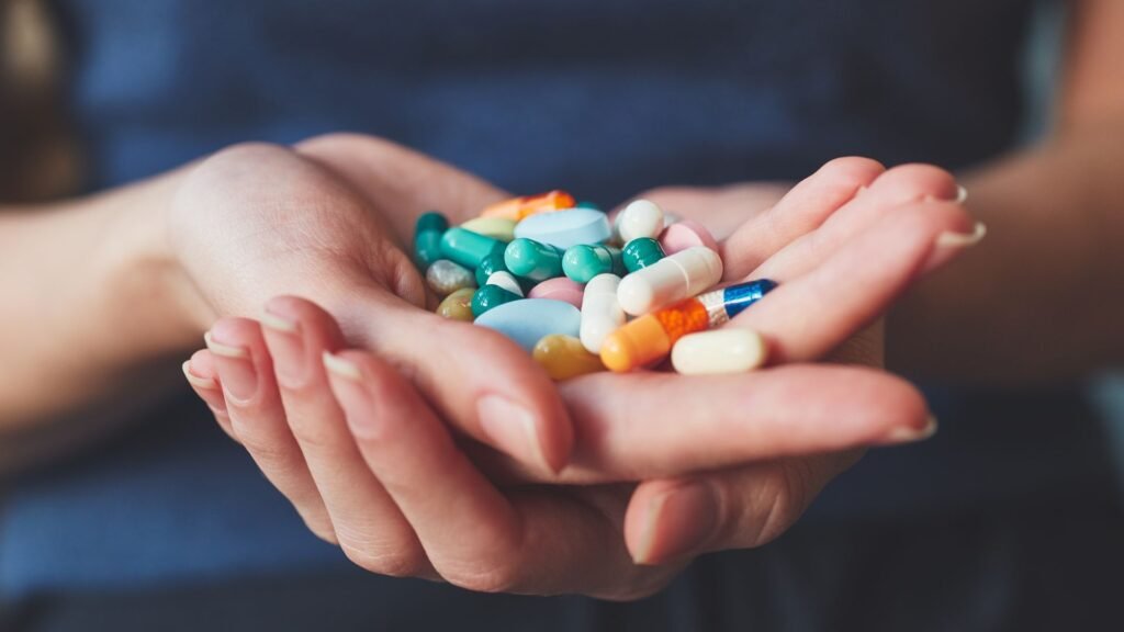 A hand holding a collection of multicolored pills, showcasing the range of dietary supplements or medications.