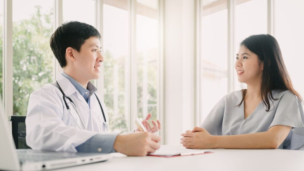 A doctor and patient engage in a discussion during a medical consultation in a bright, well-lit room.